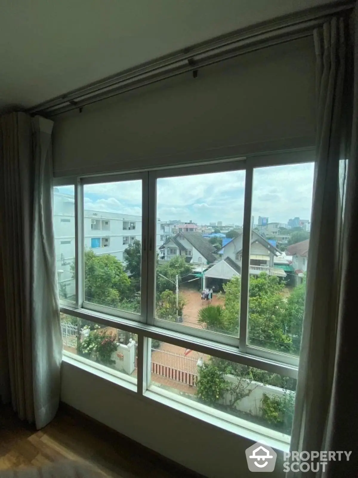 Spacious room with large window offering a scenic view of suburban neighborhood.