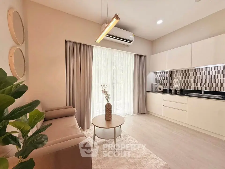 Modern living room with stylish kitchen, featuring sleek cabinetry and elegant decor.