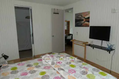 Cozy bedroom with modern decor and wall-mounted TV in a stylish apartment.