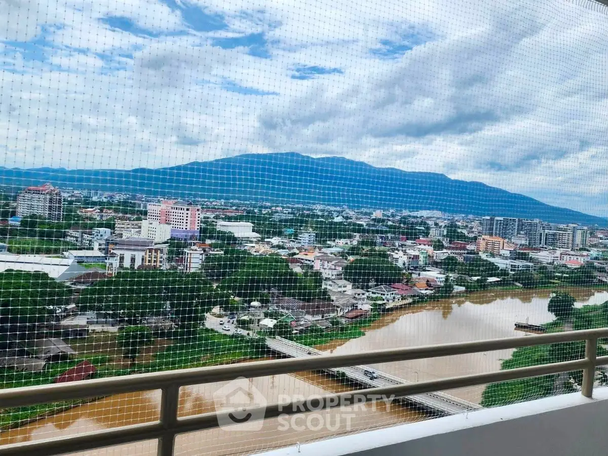 Stunning cityscape view from high-rise balcony overlooking river and mountains.