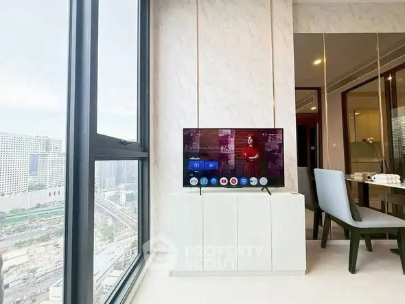 Modern living room with large window offering stunning city view and sleek TV setup.