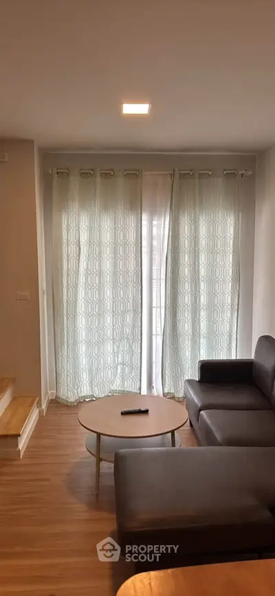 Modern living room with stylish furniture and natural light through large windows.