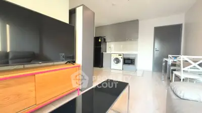 Modern open-plan living room with kitchen, featuring a washing machine and sleek appliances.