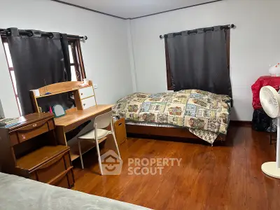 Cozy bedroom with wooden flooring, desk, and bed, ideal for comfortable living.