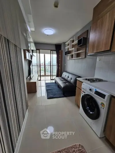 Modern living room with balcony view, stylish furniture, and in-unit washing machine in a compact apartment.