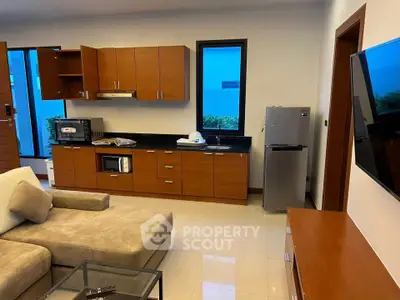 Modern open-layout living room with kitchen, featuring sleek wooden cabinets and cozy seating area.