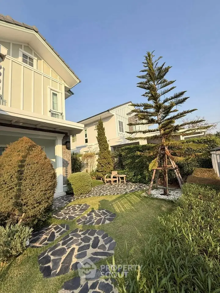 Charming suburban home with lush garden and stone pathway under clear blue sky.