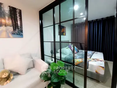 Modern apartment with glass partitioned bedroom and cozy living area, featuring stylish decor and natural light.