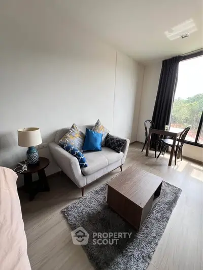 Modern living room with cozy sofa, stylish decor, and natural light from large window.
