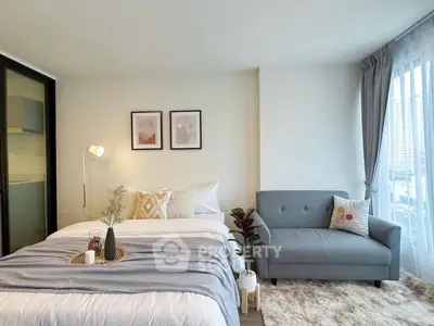 Modern bedroom with cozy decor and city view, featuring a stylish bed and a comfortable sofa.