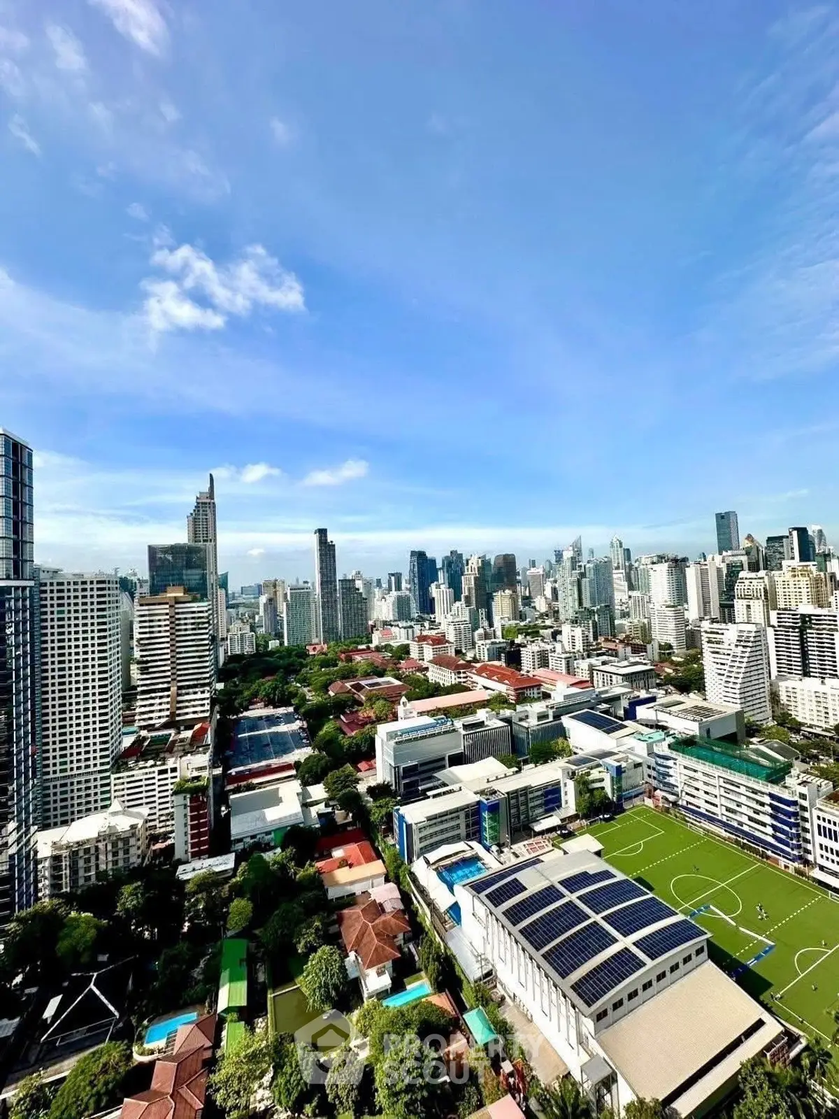 Stunning cityscape view with lush greenery and modern skyscrapers under a clear blue sky.