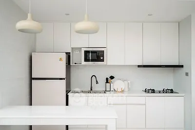 Modern kitchen with sleek white cabinets and gas stove, featuring minimalist design and ample storage.