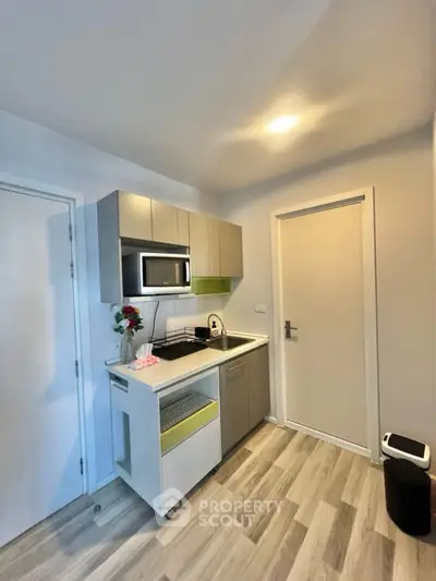 Modern compact kitchen with sleek cabinetry and microwave in cozy apartment