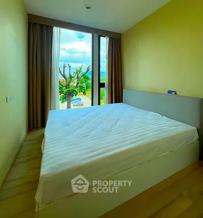 Cozy bedroom with large window and scenic view, perfect for relaxation.