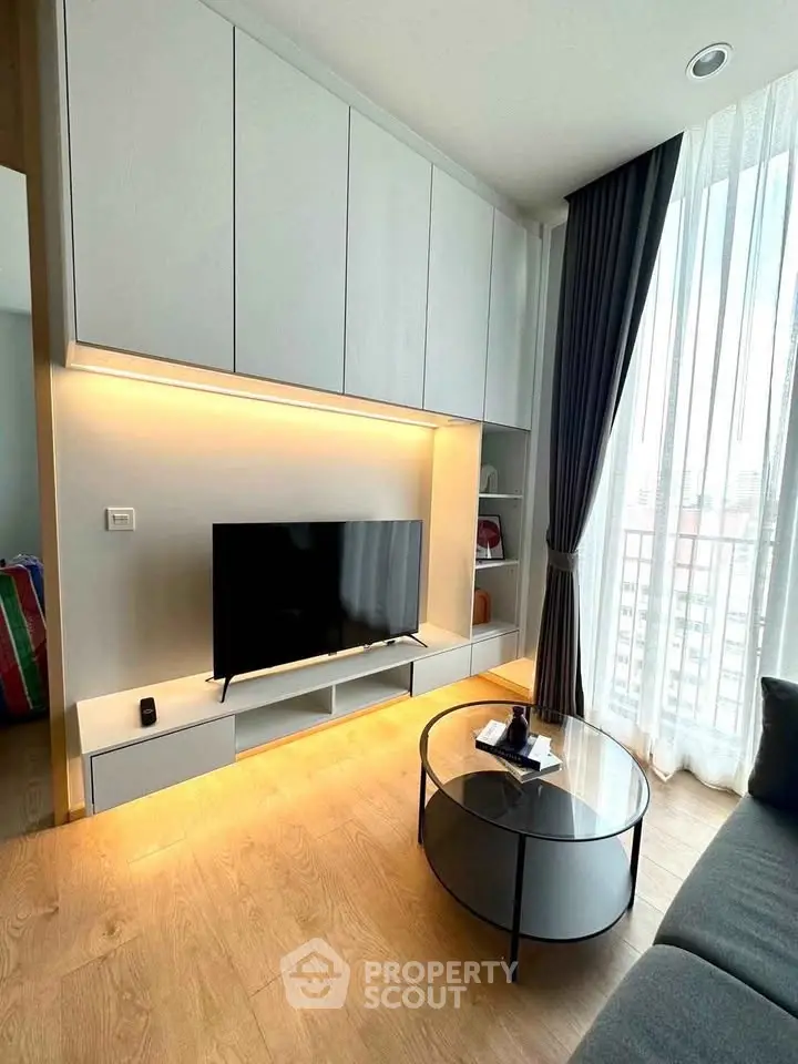 Modern living room with sleek TV unit and large window offering city views.