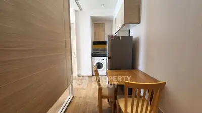 Compact kitchen with wooden dining set and modern appliances in cozy apartment.