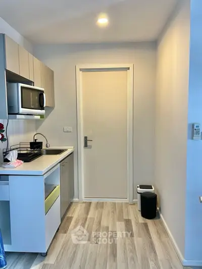 Modern compact kitchen with sleek cabinetry and built-in microwave