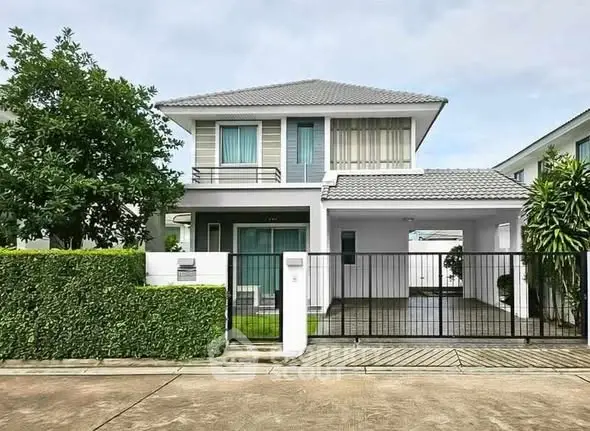 Modern two-story house with gated driveway and lush greenery.