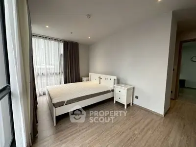 Spacious modern bedroom with large window and elegant furnishings in a stylish apartment.