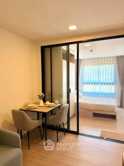 Modern studio apartment with sliding glass doors separating bedroom and dining area.