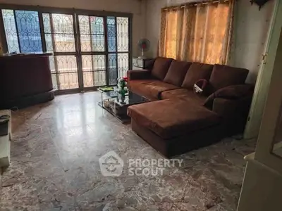 Spacious living room with large windows and comfortable brown sectional sofa.