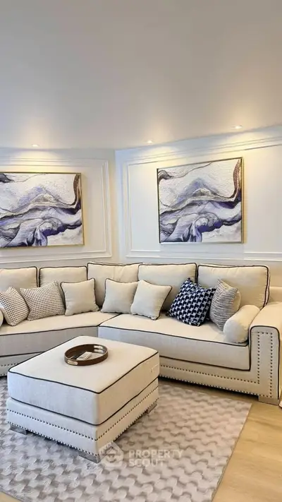Elegant living room with plush beige sofa, stylish artwork, and cozy ambiance.