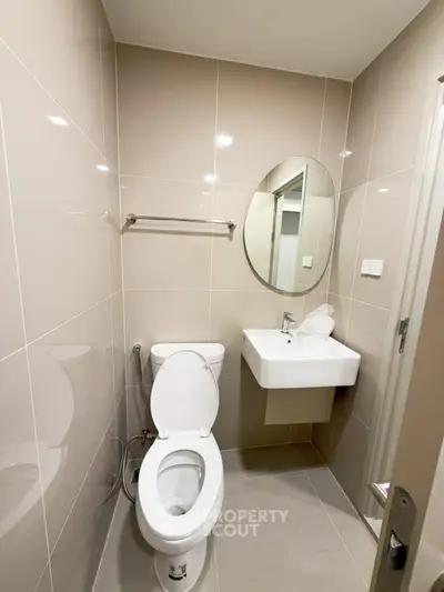 Modern bathroom with sleek design featuring a round mirror and compact sink.
