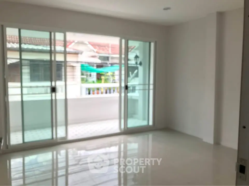 Spacious living room with large sliding glass doors leading to a balcony, offering ample natural light.