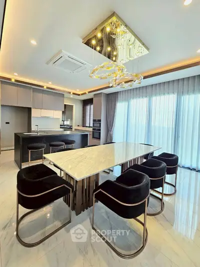 Luxurious modern kitchen with marble island and elegant lighting in a spacious open layout.