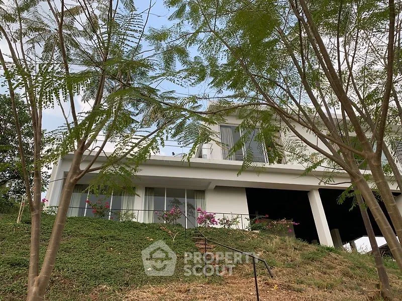 Modern hillside home with lush greenery and spacious balcony