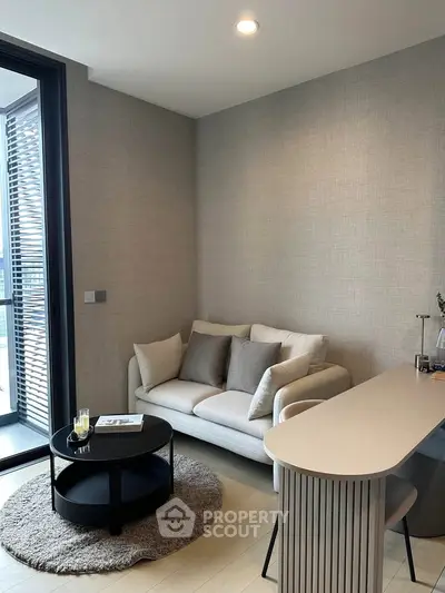 Modern living room with cozy sofa and stylish decor, featuring a sleek round coffee table and a view of the balcony.