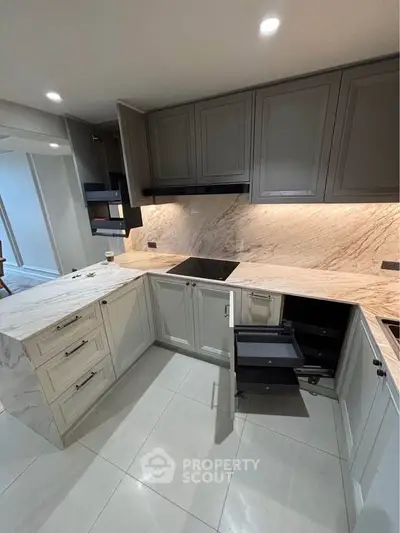 Modern kitchen with marble countertops and sleek cabinetry, featuring an open layout and induction cooktop.