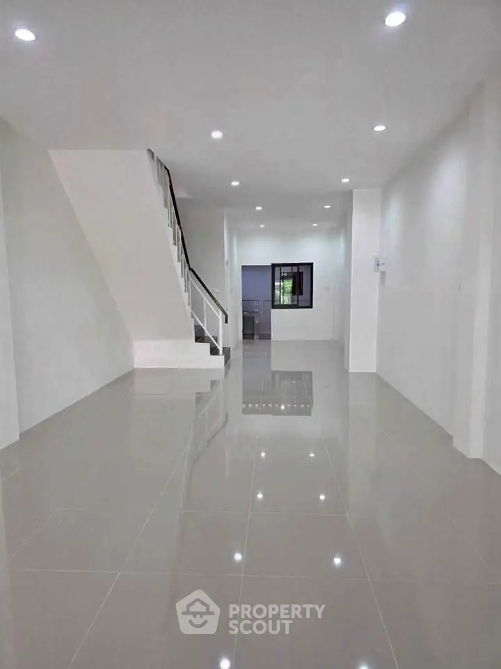Spacious modern interior with glossy tiled floors and staircase, perfect for customization.