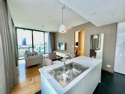 Modern open-plan living room with city view, featuring sleek kitchen island and stylish decor.