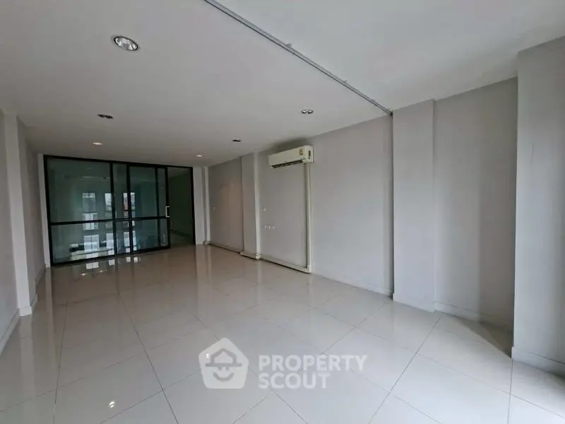 Spacious unfurnished living room with air conditioning and large windows in modern apartment.