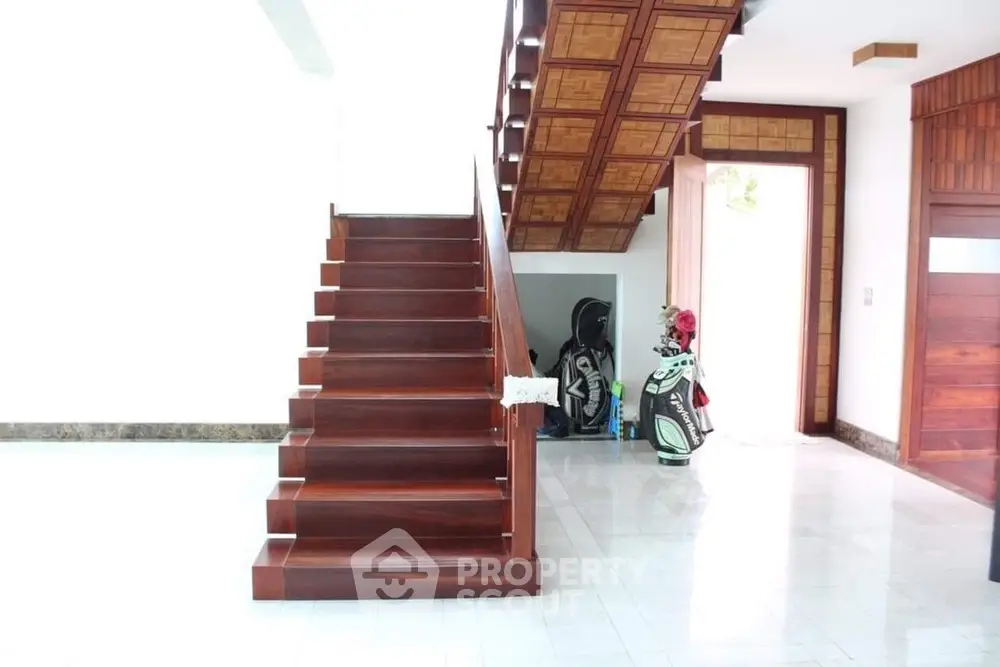 Elegant wooden staircase in modern home with golf equipment storage