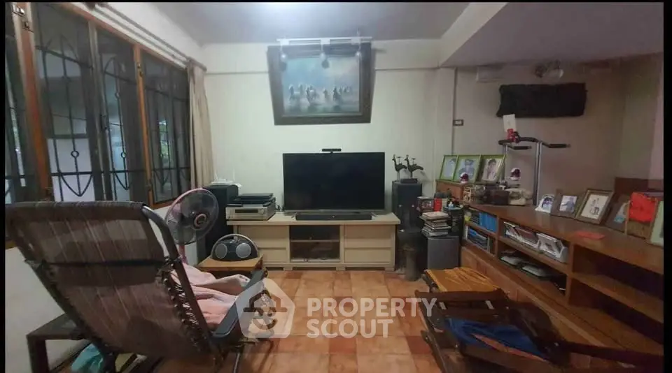 Cozy living room with tiled floor, entertainment center, and large window view.