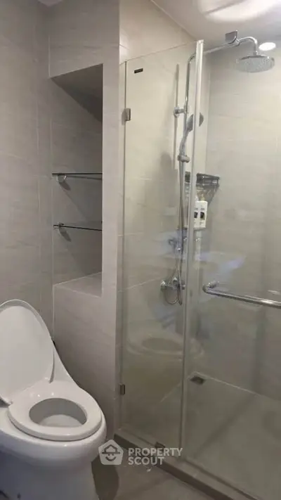 Modern bathroom with glass shower and sleek toilet in contemporary apartment.