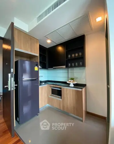 Modern compact kitchen with sleek cabinetry and stainless steel appliances in a stylish apartment.