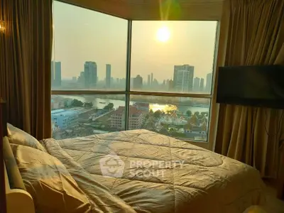 Luxurious bedroom with stunning city skyline view through large windows at sunset.