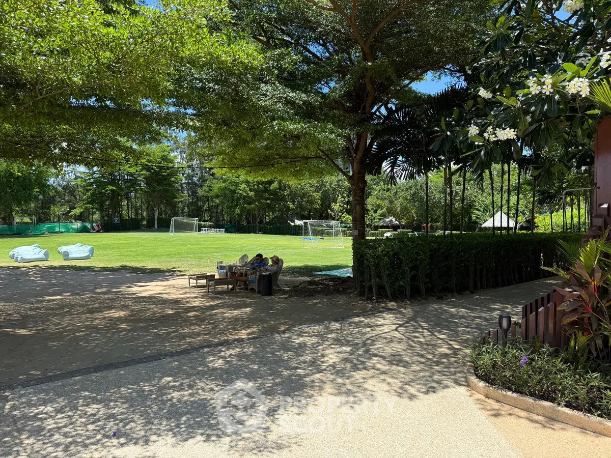 Spacious outdoor garden area with lush greenery and soccer field, perfect for recreation and relaxation.