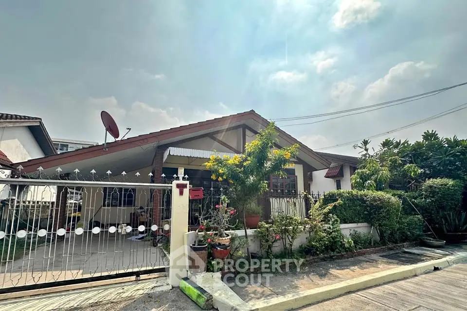 Charming suburban house with lush garden and gated driveway under a clear sky.