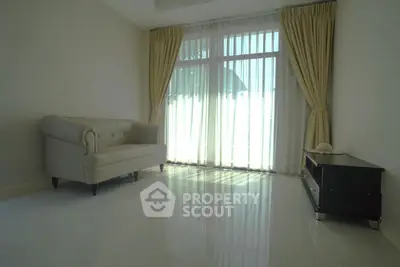 Spacious living room with elegant sofa and large window with curtains
