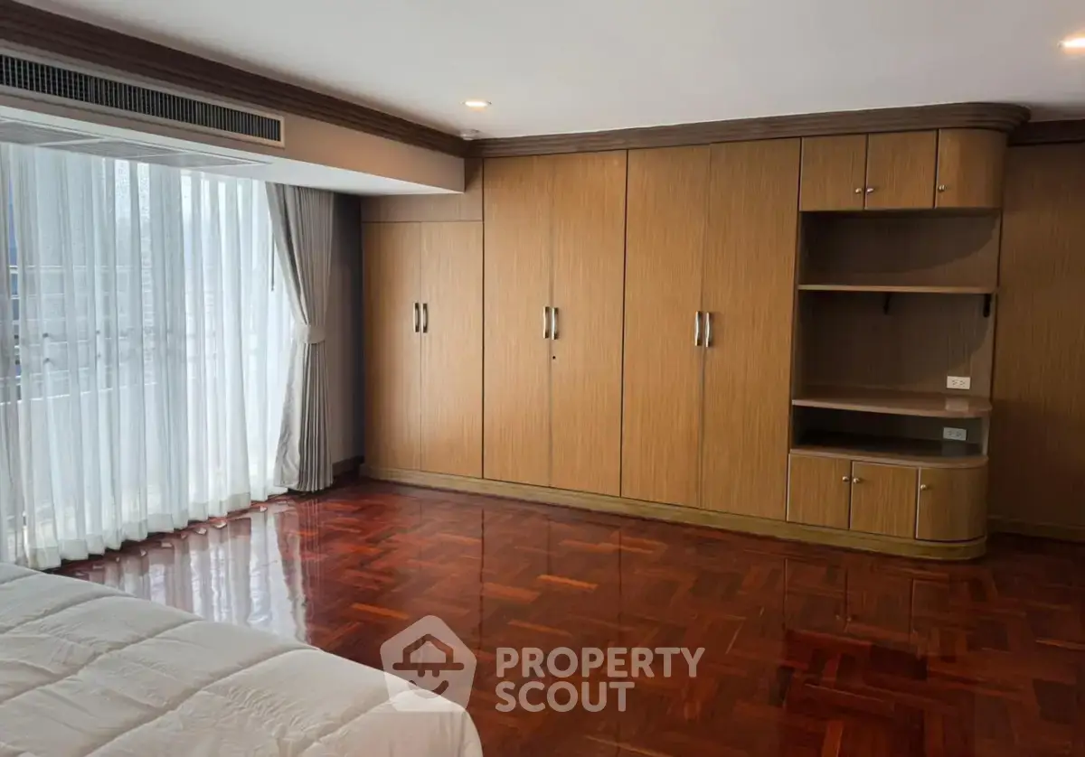 Spacious bedroom with elegant wooden flooring and built-in wardrobe, perfect for modern living.