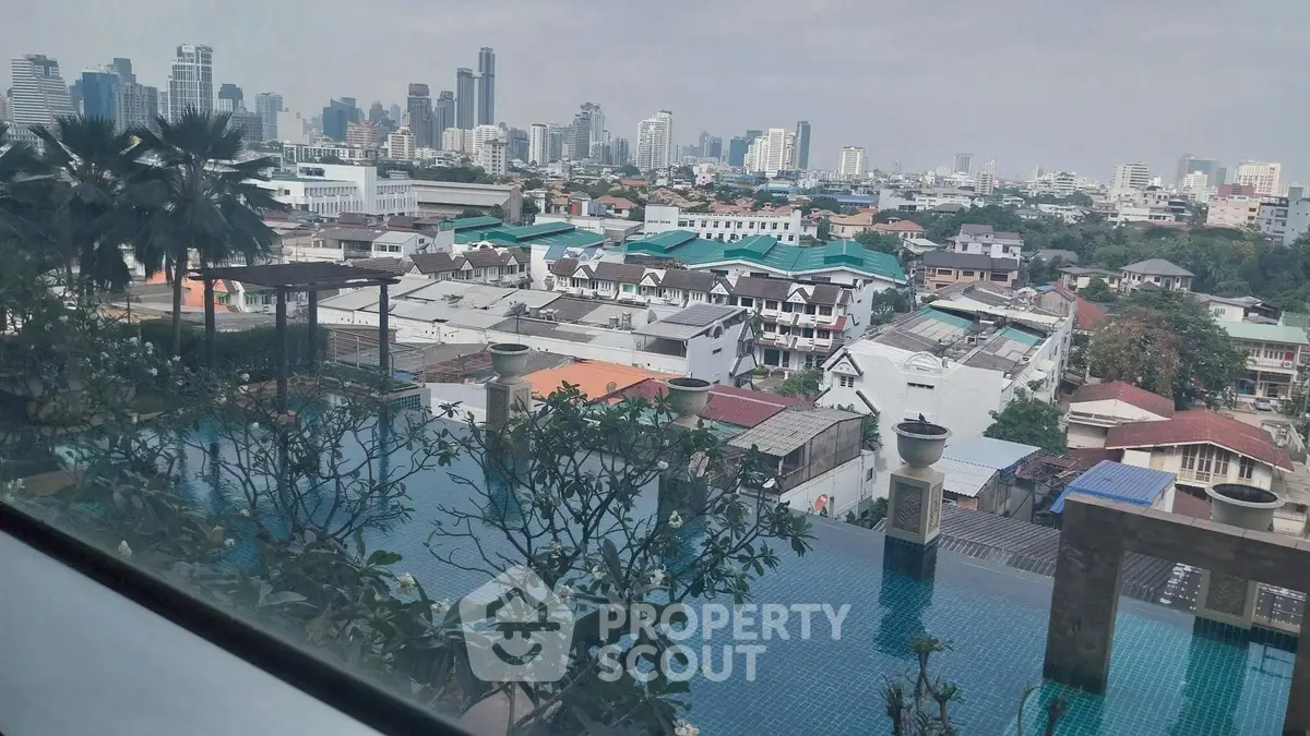 Stunning cityscape view from rooftop pool overlooking urban skyline and residential area.