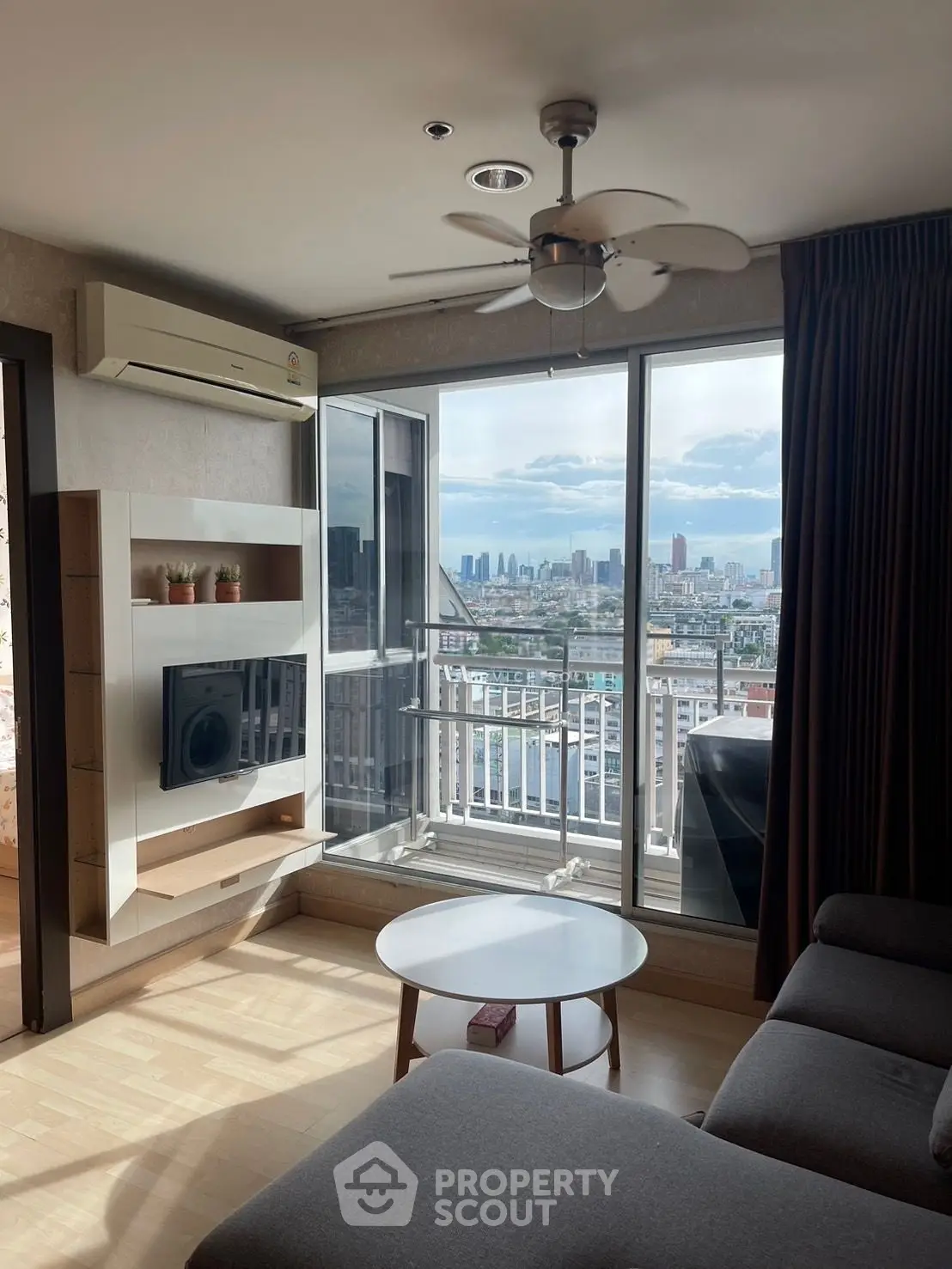 Modern living room with city view, featuring sleek furniture and large windows for natural light.