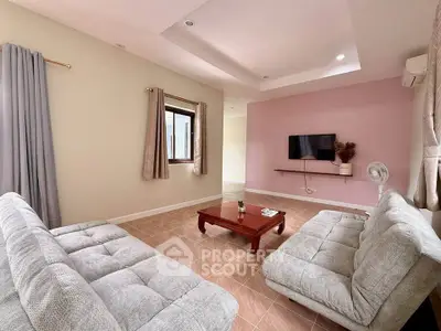Spacious living room with modern sofas and wall-mounted TV, perfect for relaxation and entertainment.