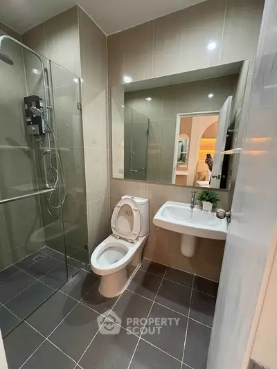 Modern bathroom with glass shower and sleek fixtures in contemporary apartment.