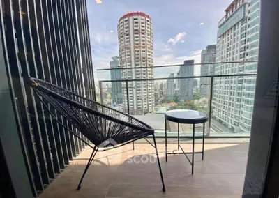 Stylish balcony with modern chair and table offering stunning city skyline views.