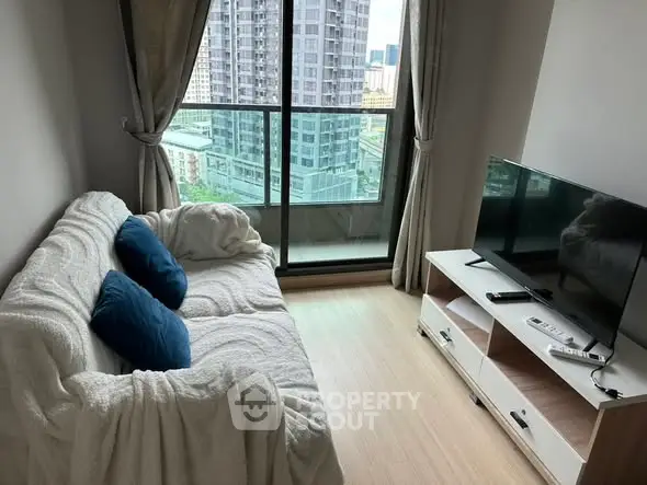 Cozy living room with city view, featuring a comfortable sofa and modern TV setup.